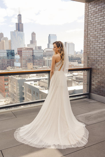 Full length, bride looks at camera over her shoulder with Chicago, IL in the background